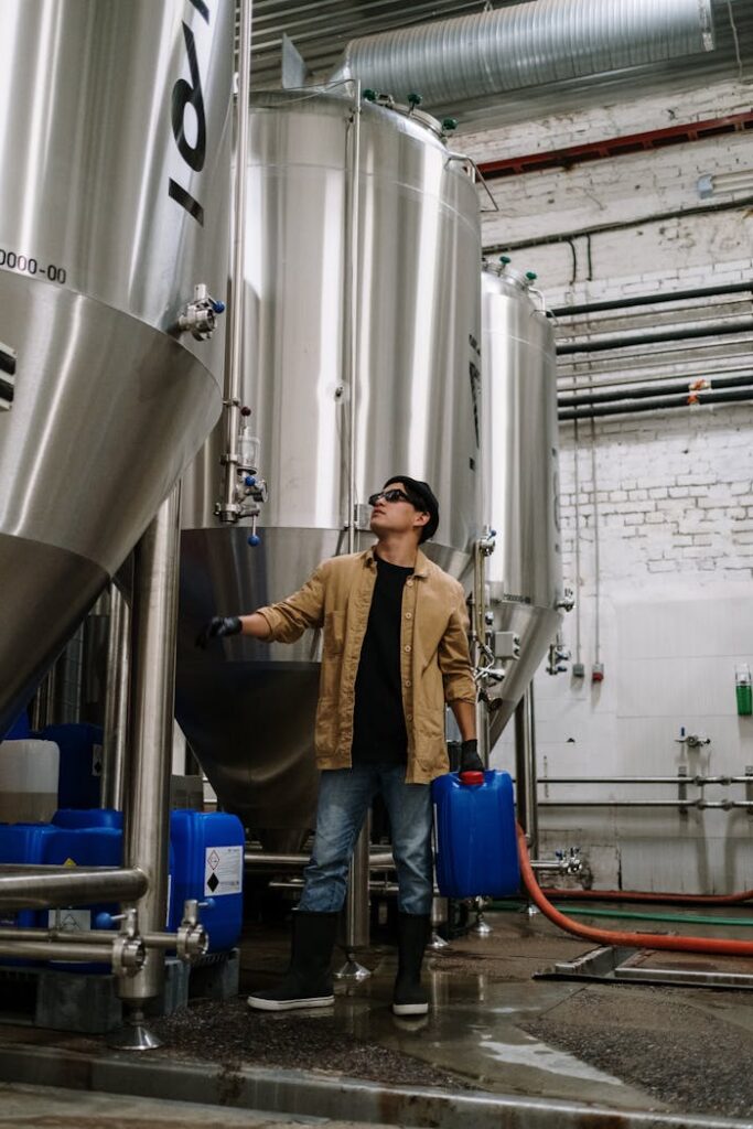 pexels-photo-5532989 Man in industrial setting checking stainless steel brewing equipment.